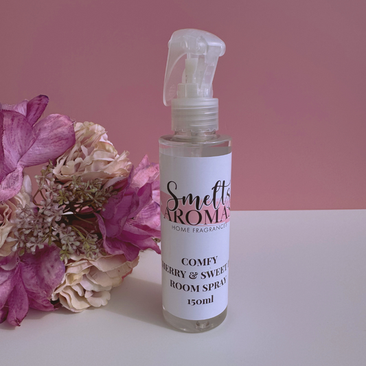 Smelt's Aromas Comfy Cherry & Sweet Pea room spray bottle with flowers on a pink background