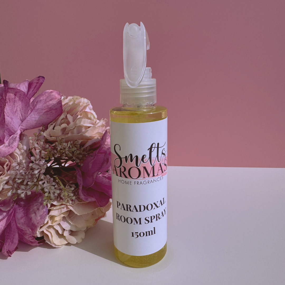 Bottle of Smelt's Aroma Paradoxical Room Spray with flowers on a pink background
