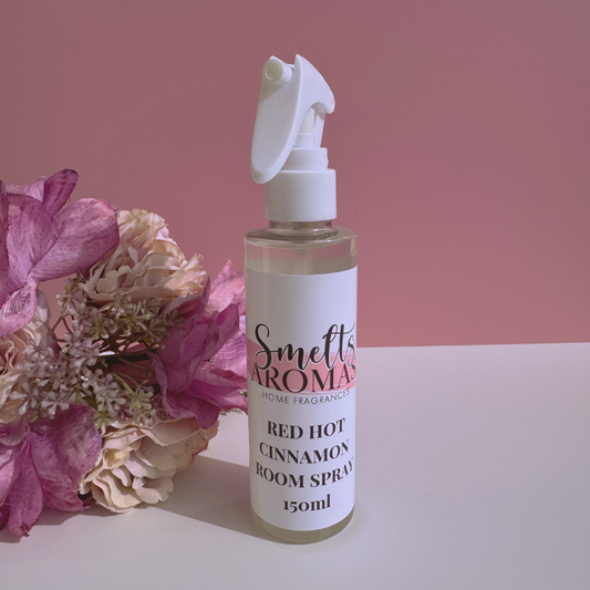Red Hot Cinnamon room spray bottle from Smelts Aromas with flowers on a pink background